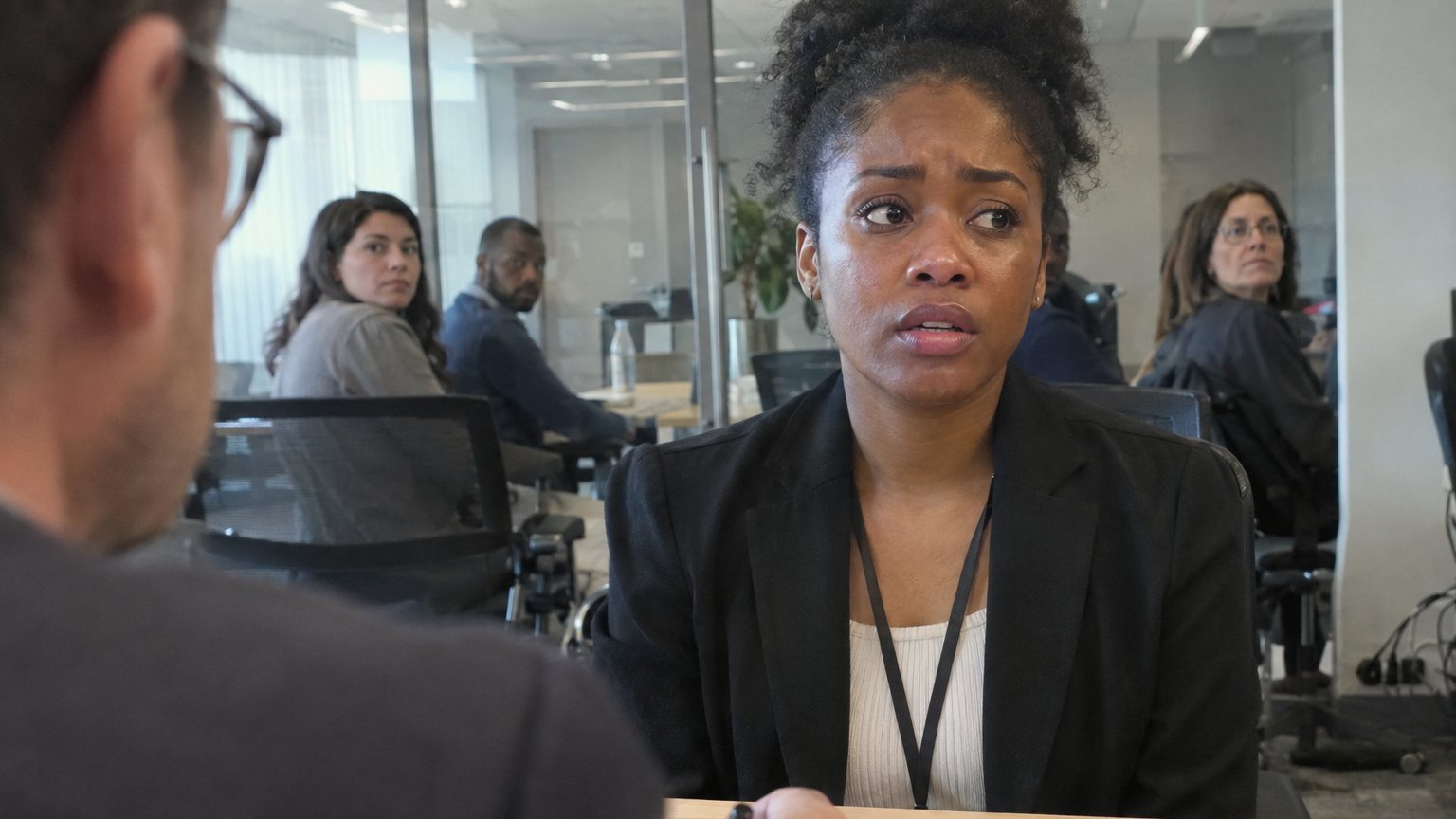 A job candidate pauses during the opening interview question while an interviewer waits with a pen over a resume