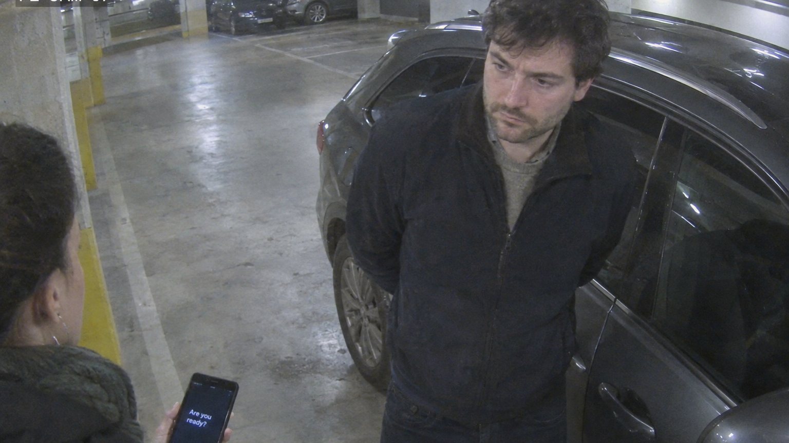 Security camera view of a man frozen on office stairwell steps with his hands clasped behind his back