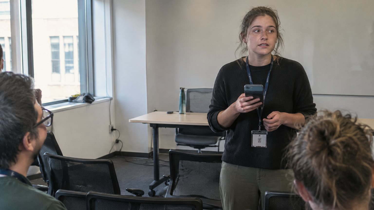 A professional practices a short talk into a phone in an empty conference room