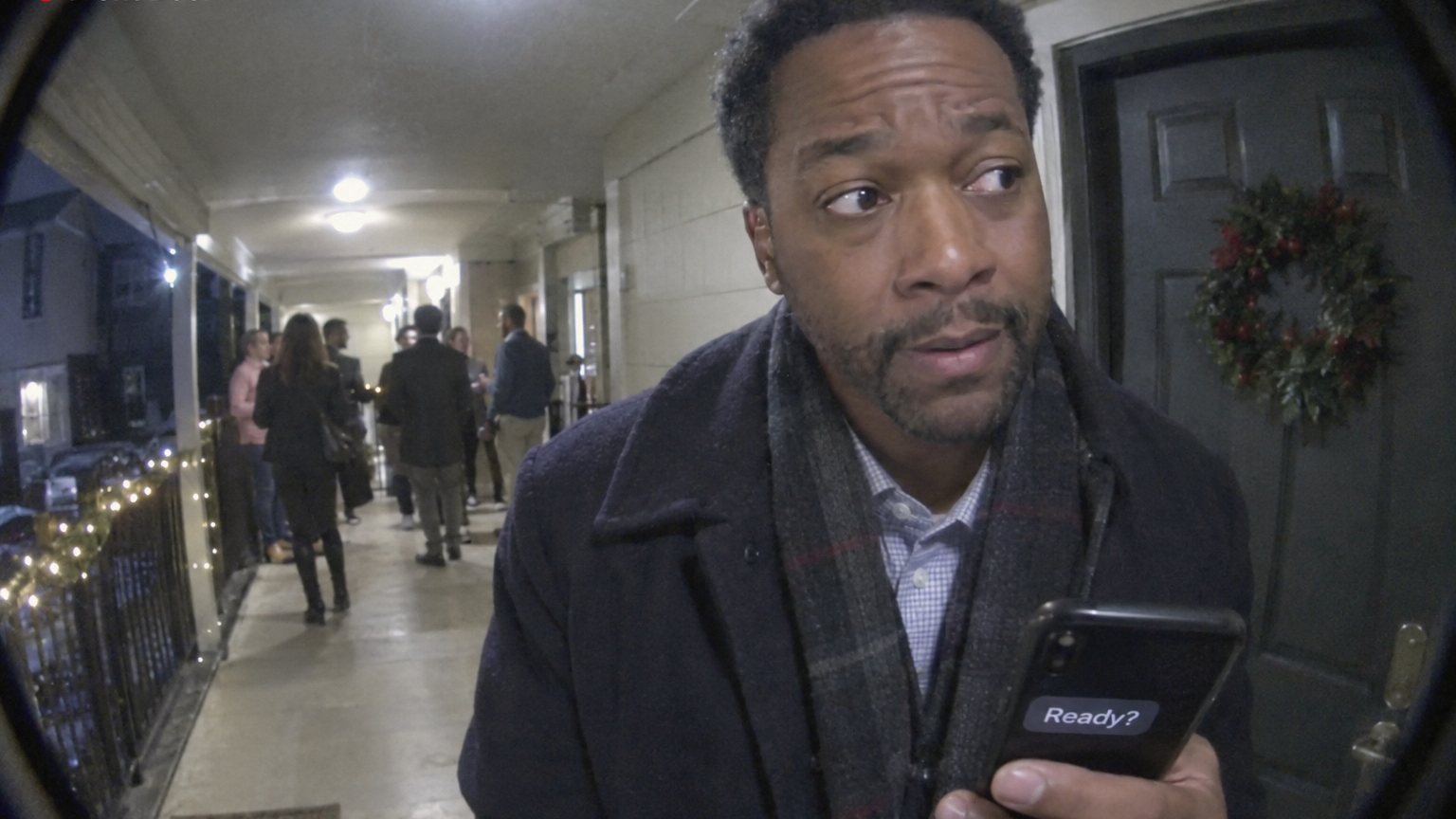 A Black man outside an apartment door rehearses before entering a work holiday gathering